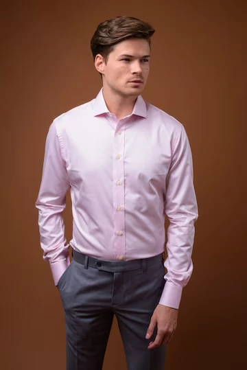 En ung mann med en rosa skjorte med ekstra lange ermer.